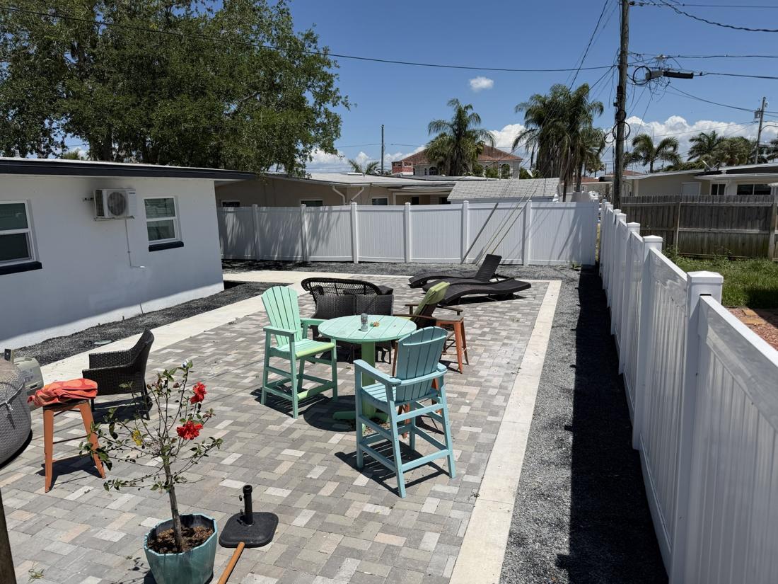 Paver patio with gravel borders and a white vinyl fence in St. Petersburg, FL